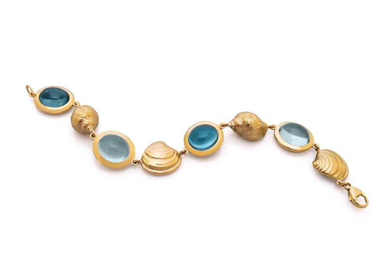 A blue Topaz cabochon and 18 carat gold bracelet featuring solid gold casts of shells collected from Readymoney Cove, Fowey, Cornwall - A bespoke 'Those Happy Places' commission.